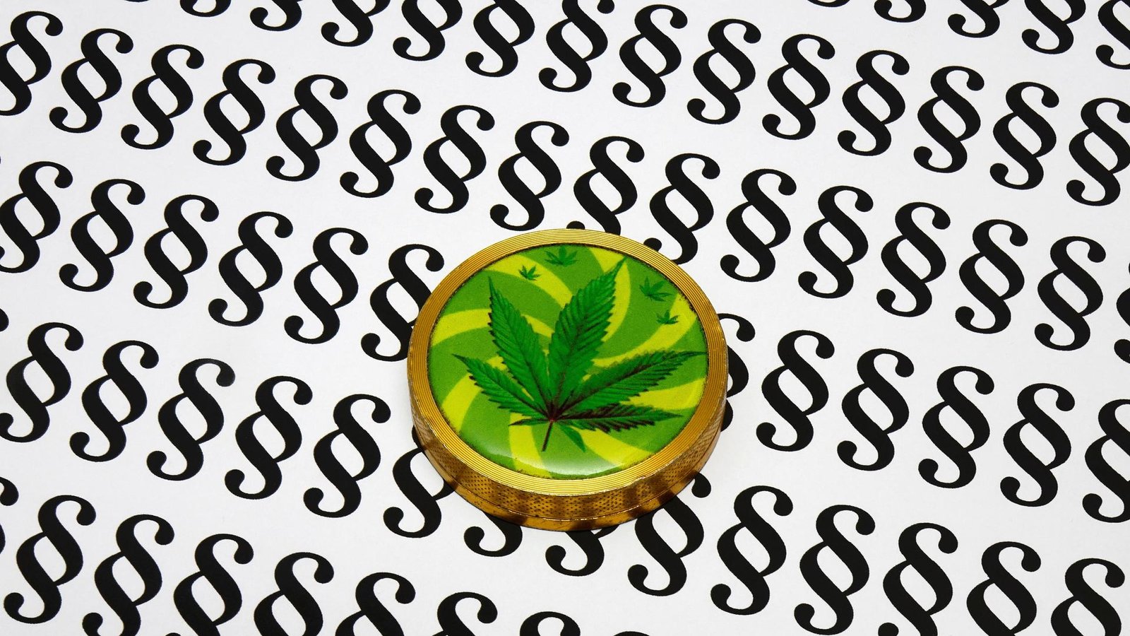 Eine Cannabisdose liegt auf einem Blatt voller Paragraphen. Eine Cannabisdose liegt auf einem Blatt voller Paragraphen.